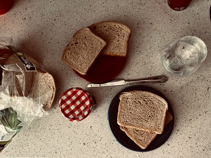 a breakfast setting, toast, a glass of water, and a jam jar, from above